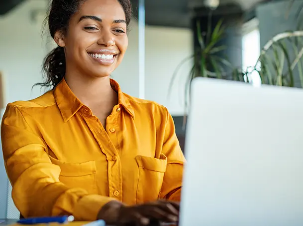 Woman working on a laptop in a an office setting.